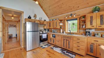 A wooden kitchen with a stainless steel refrigerator, wooden cabinets, and a window providing natural light.
