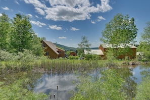 Eine rustikale Holzhütte, umgeben von üppigem Grün und einem kleinen Teich.