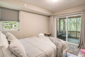 A bedroom with a bed, a small table, and a view of a balcony with outdoor furniture. - Massanutten Resort Home w/ Hot Tub & Game Room! (McGaheysville)
