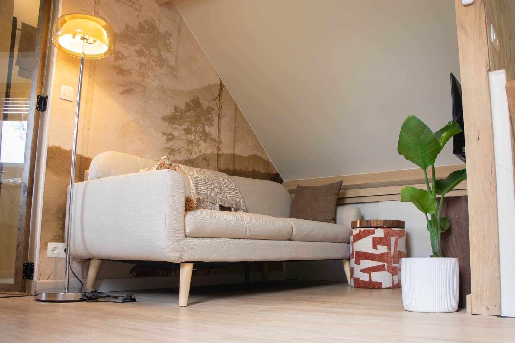 Un salon moderne avec un canapé, une lampe sur pied, une plante en pot et un vase décoratif.