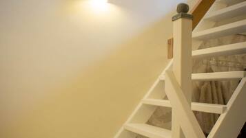 Een trap met witte leuningen en een houten handrail, leidend naar een plateau met een lamp.