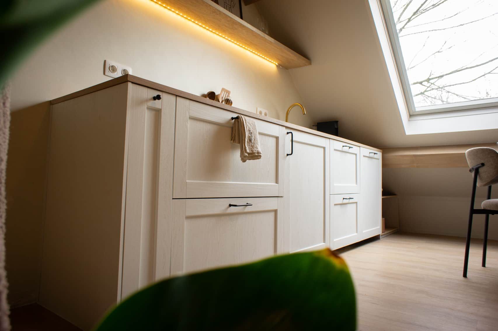 A modern kitchen with white cabinetry, a visible towel, and a skylight.