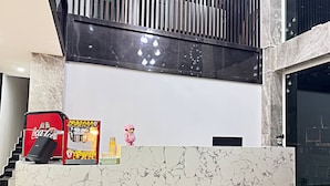 A reception desk with a Coca-Cola vending machine, a small toy figure, and a marble-patterned wall. - The Movie Hotel by Mecon (Phnom Penh)