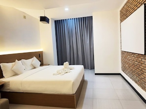 Ein Hotelzimmer mit einem großen Bett, einem flachbildfernseher an der Wand und einem Projektor an der Decke.