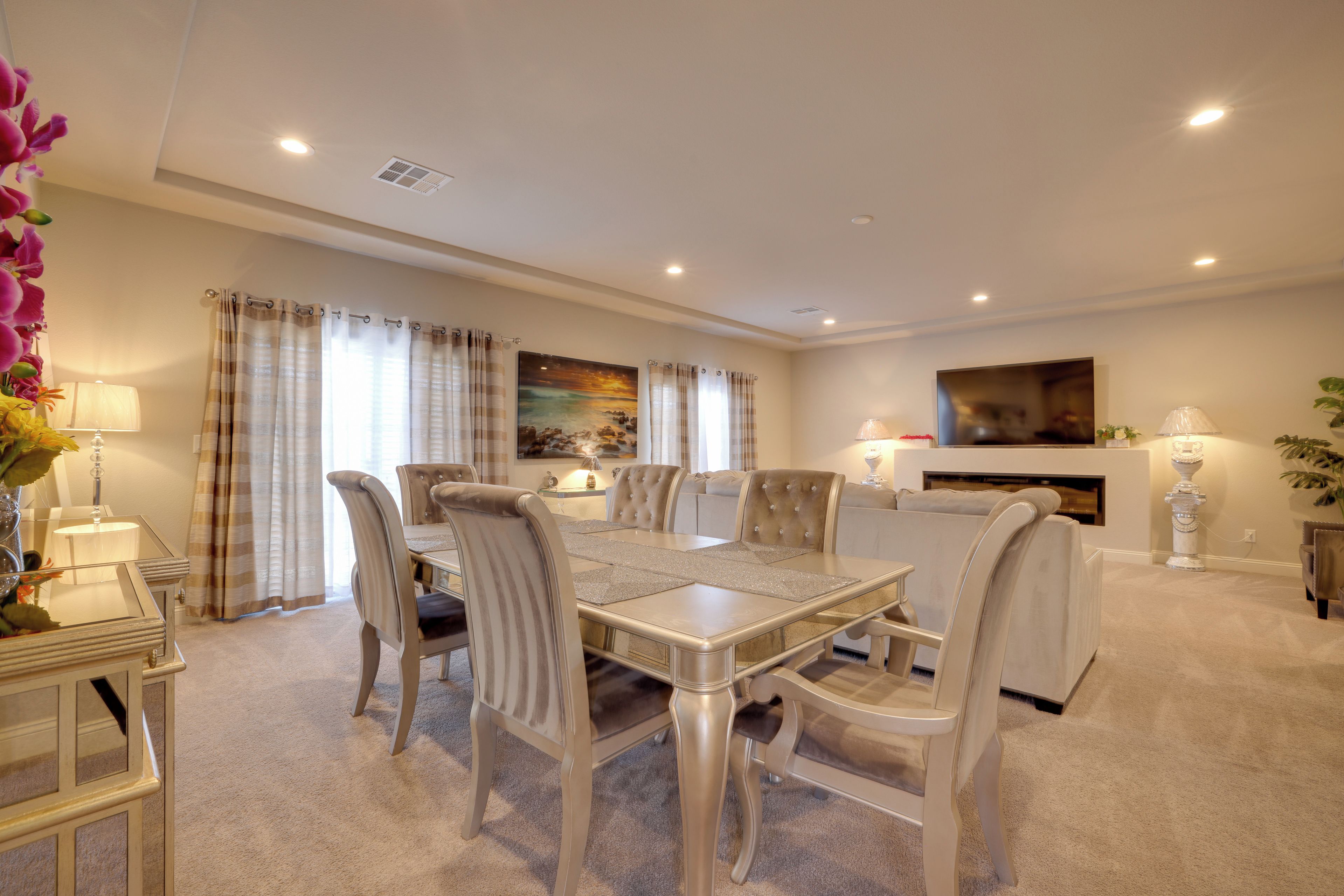 A dining area with a table and chairs, a sofa, a TV, and a fireplace.