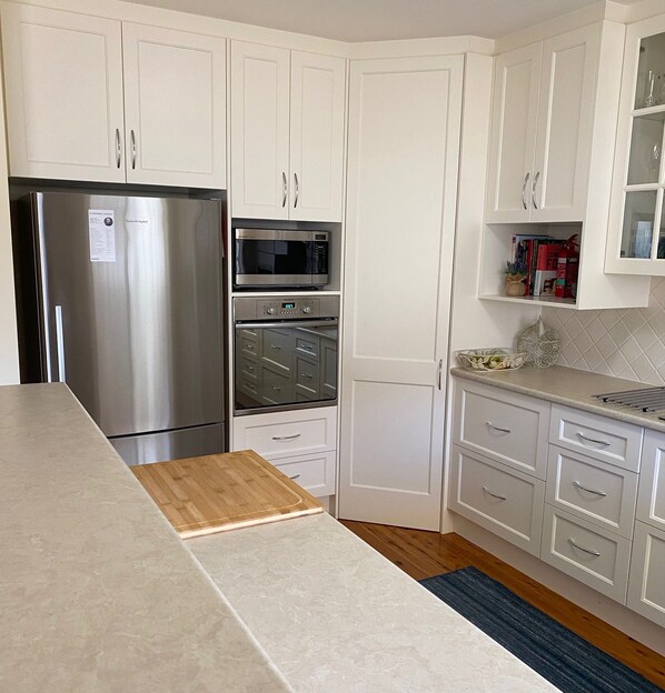 A kitchen with white cabinets, a stainless steel refrigerator, a microwave, and an oven.