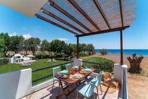 A terrace with a table set for dining, overlooking a beach and a clear sky. - Eco Beach And Magic Garden  (Rhodes)