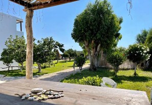 Un muelle de madera con piedras y un banco, rodeado de árboles y un cielo despejado.
