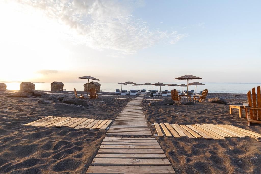 Un sentiero di legno che conduce a ombrelloni e lettini su una spiaggia sabbiosa.