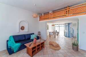 Una sala de estar con sofá, mesa de centro y comedor con sillas y una mesa.