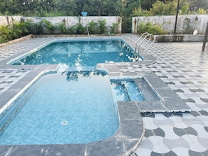 A swimming pool with a tiled deck and a metal ladder.