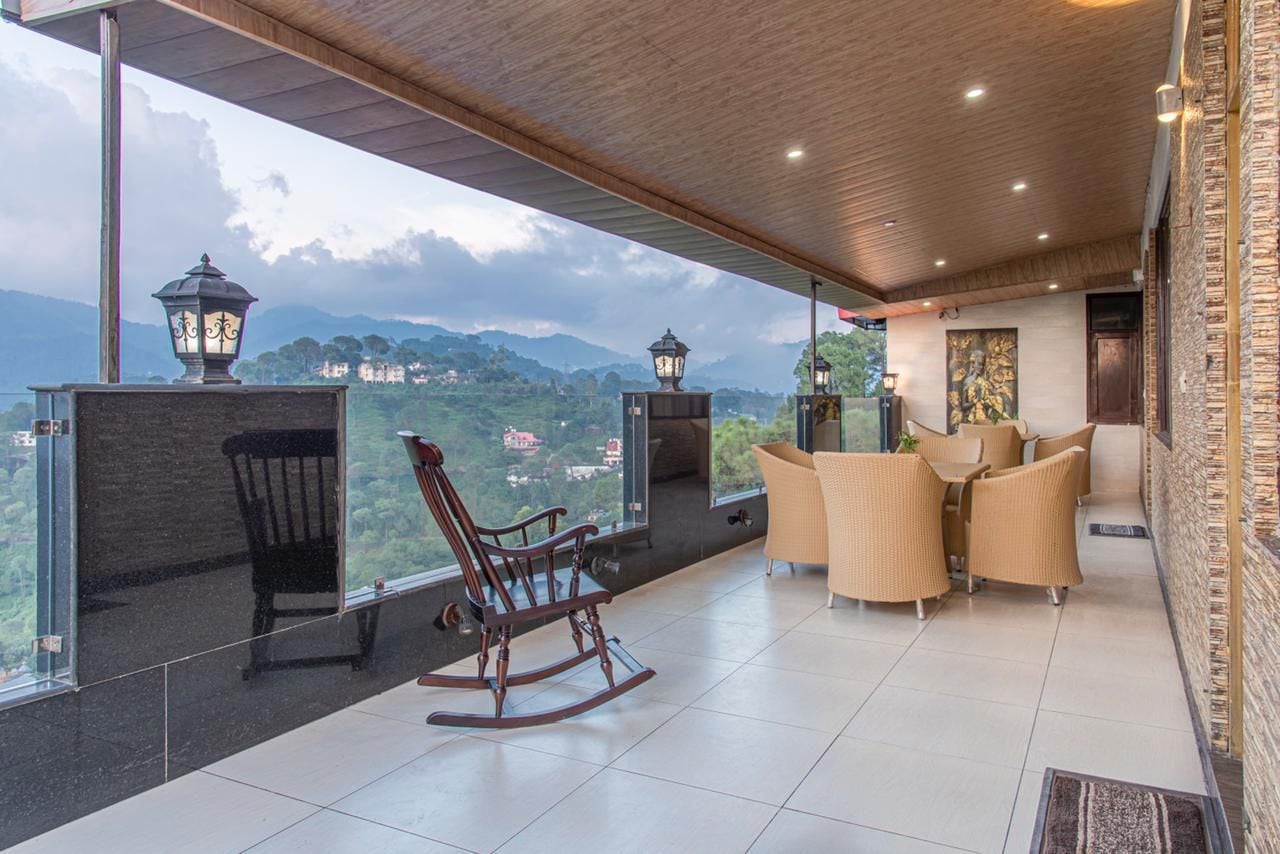 A balcony with a view of a mountainous landscape, furnished with wicker chairs and a rocking chair.