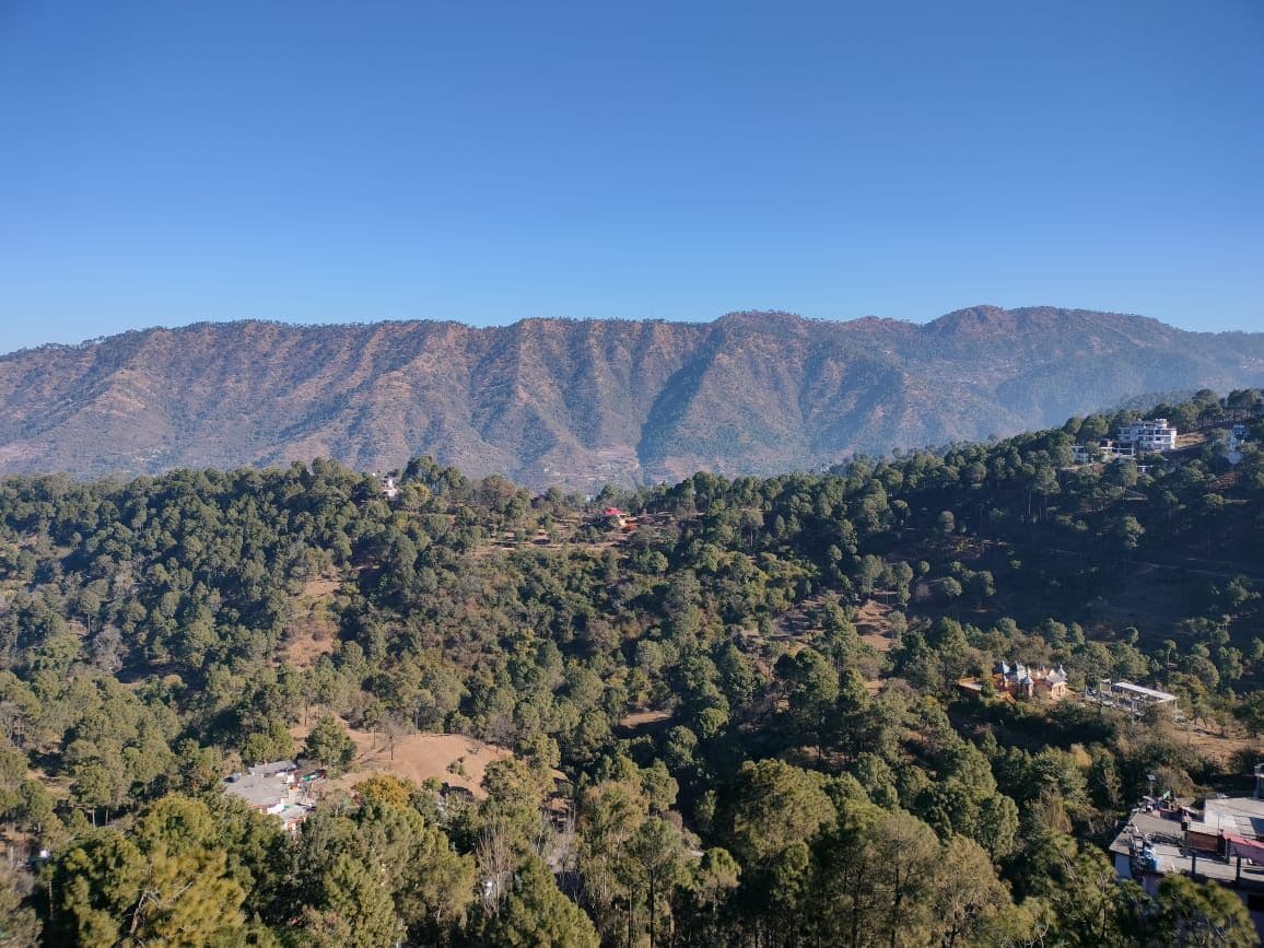 A mountainous landscape with scattered buildings and dense forest.