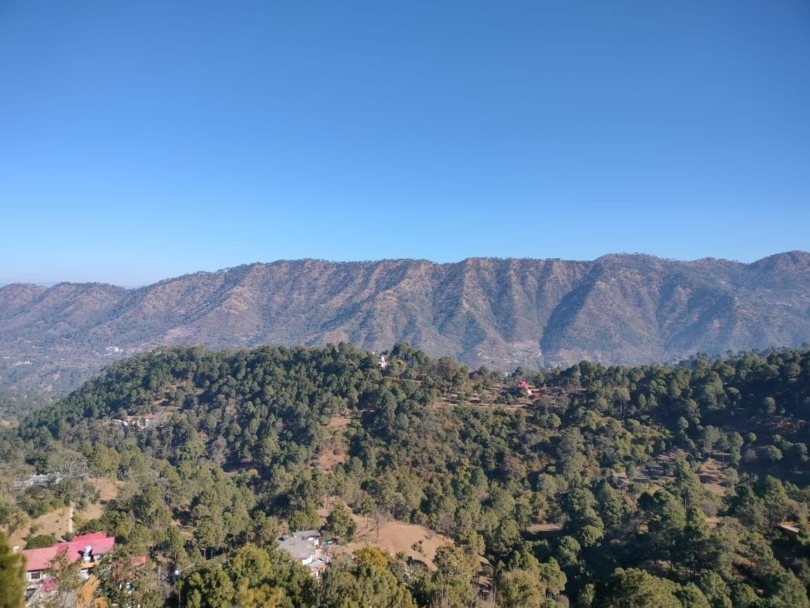 Un paisaje montañoso con densa vegetación y edificios dispersos.