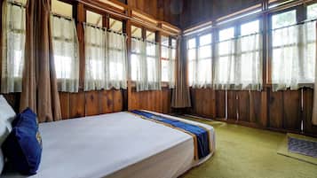 Una habitación con una cama grande, paredes de madera y varias ventanas con cortinas.