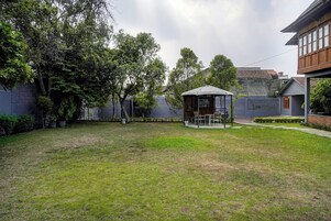 Un patio con un pabellón, un césped y un edificio con pared de piedra.