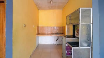 A narrow hallway with a kitchen area featuring a sink, cabinets, and a tiled floor.