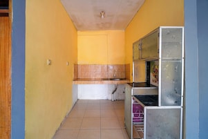 Un pasillo estrecho con una zona de cocina que incluye un lavamanos, armarios y piso de baldosas.
