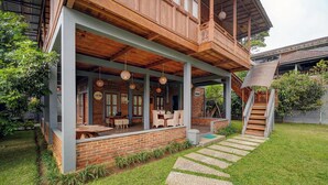 Een houten huis met twee verdiepingen, een overdekte veranda, een bakstenen gevel en een pad van stenen dat naar de ingang leidt.