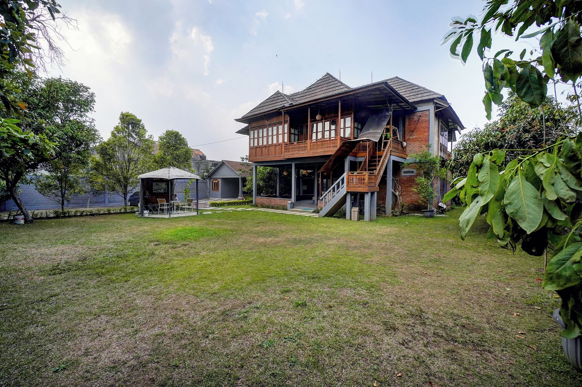 Uma casa de dois andares com varanda coberta e escada que leva ao andar superior.