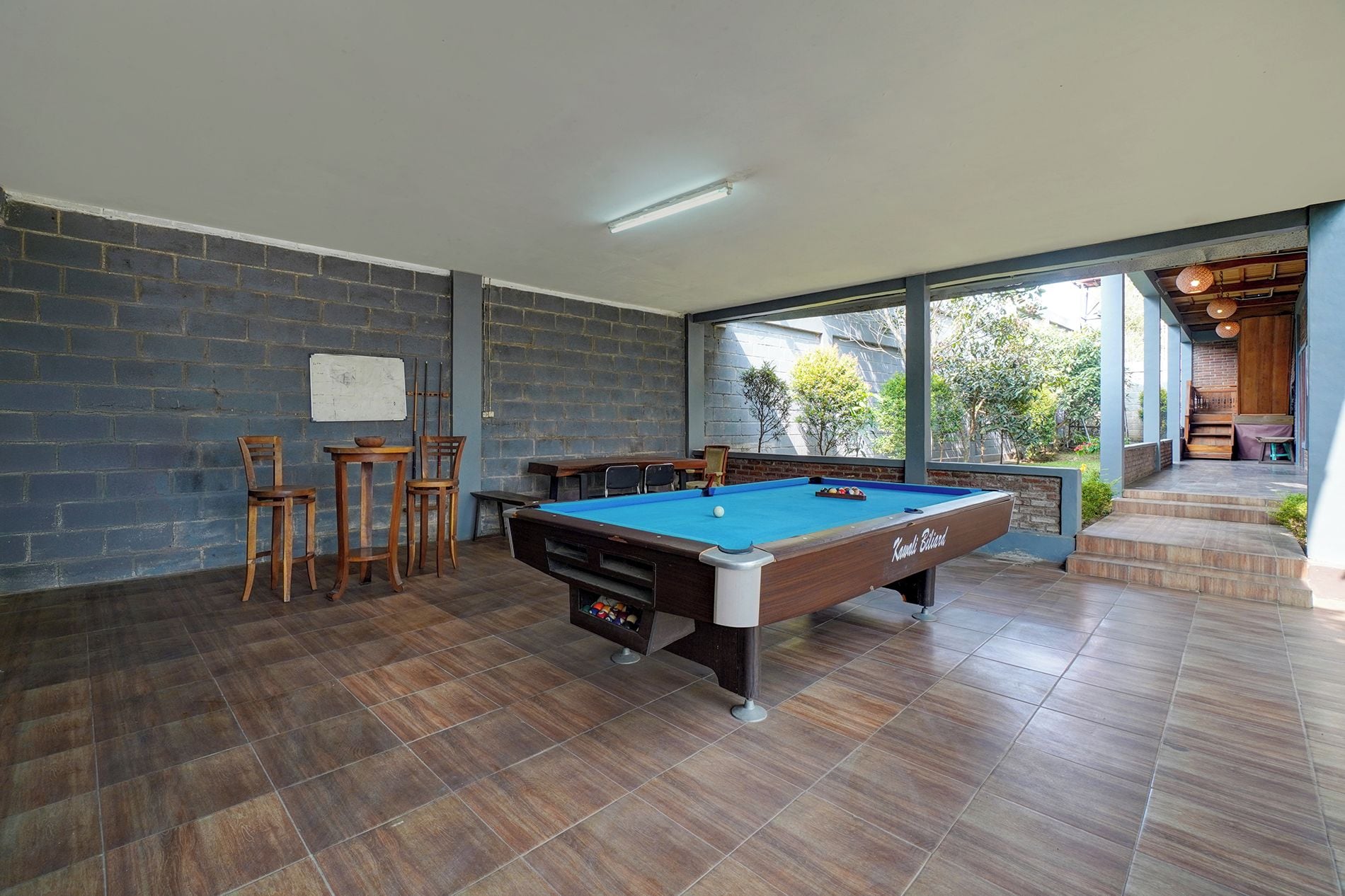 A pool table in a room with brick walls and large windows.