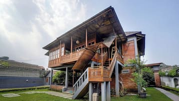 Una casa de dos pisos con un balcón, una escalera y un jardín.