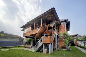 A two-story house with a balcony, a staircase, and a garden.