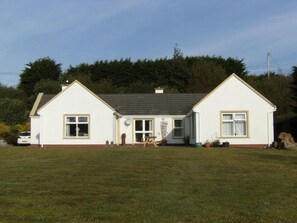 A two-story house with a front lawn, a satellite dish, and a small garden area. - WatersEdge, offers beachfront accommodation a short distance from Mulranny, (Mallaranny)