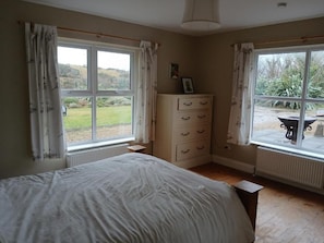 A bedroom with a bed, a dresser, and two windows with curtains. - WatersEdge, offers beachfront accommodation a short distance from Mulranny, (Mallaranny)