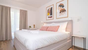 Et hotelværelse med en stor seng, et sengebord, en lampe og to billeder i rammer på væggen.