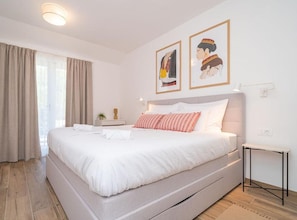 Et hotelværelse med en stor seng, et sengebord, en lampe og to billeder i rammer på væggen.