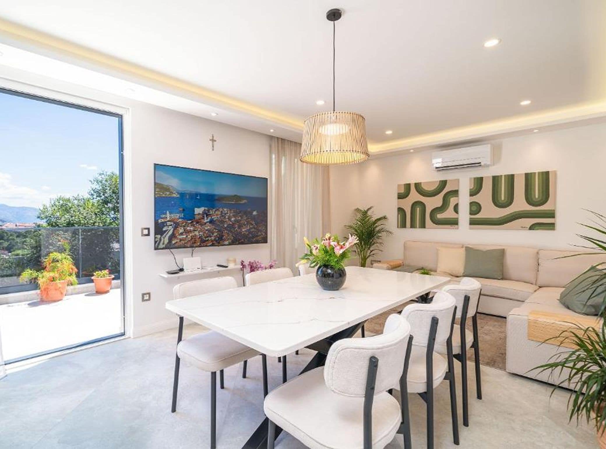 Un comedor moderno con una mesa blanca, sillas y una lámpara colgante.