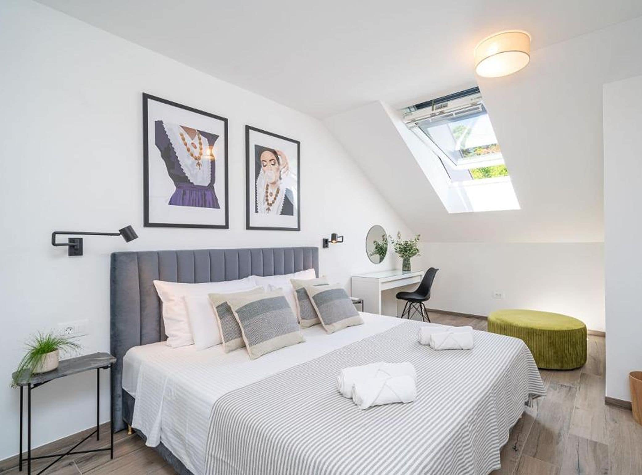 A modern bedroom with a large bed, a desk, and a skylight.