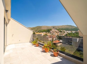 A balcony with a clear view of a town and a hill in the distance. - Luxumbra Penthouse Apartment (Dubrovnik)