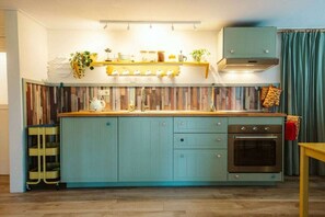 A kitchen with teal cabinetry, a wooden countertop, and a built-in oven. - Ouddorp Vakantiehuisje Zon en Zee (OUDDORP ZH)