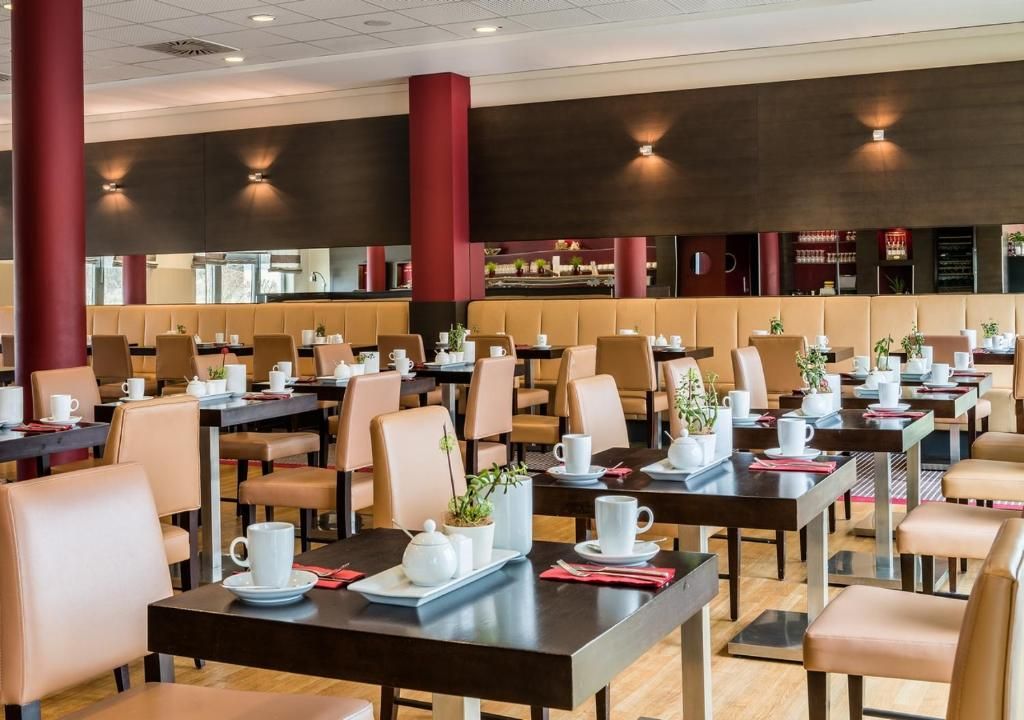 A spacious dining area with multiple tables and chairs, some with plants and tea sets.