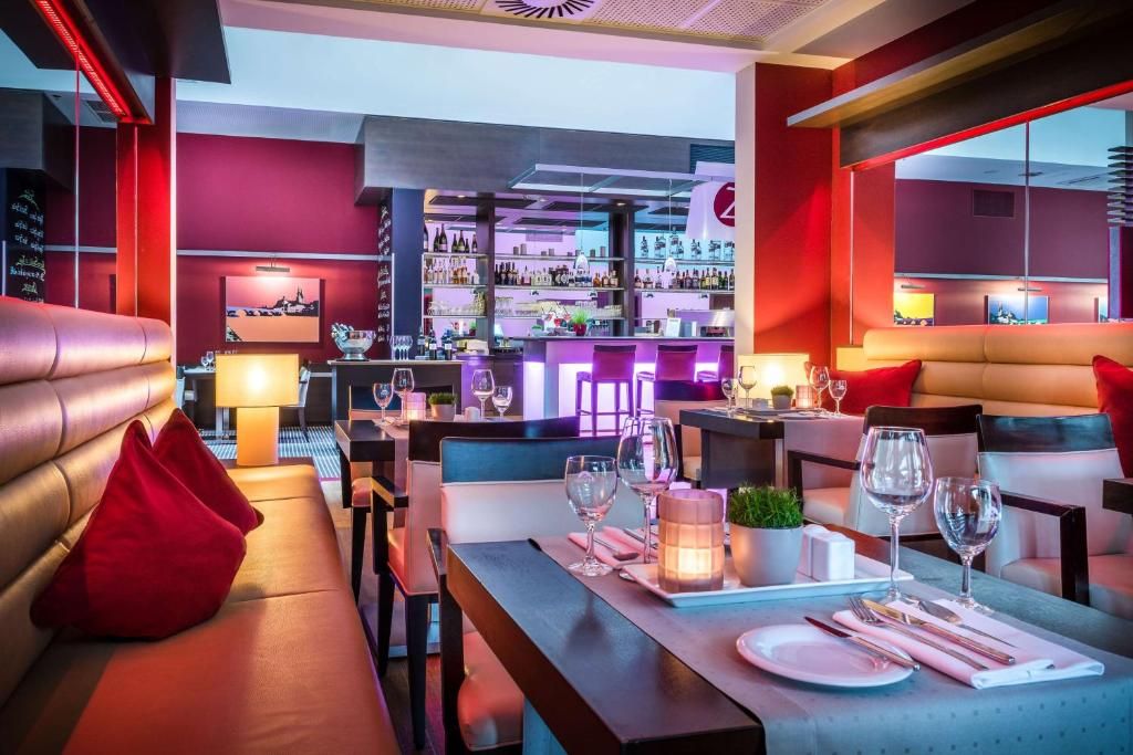 Ein Restaurant mit Barbereich, Sitzgelegenheiten mit roten Kissen und angenehmer Beleuchtung.