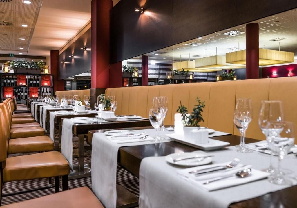 Un restaurant avec de longues tables, des banquettes et un coin bar.