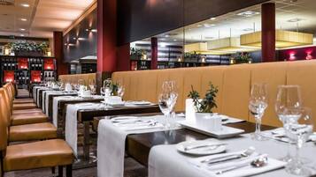 Un restaurant avec de longues tables, des banquettes et un coin bar.