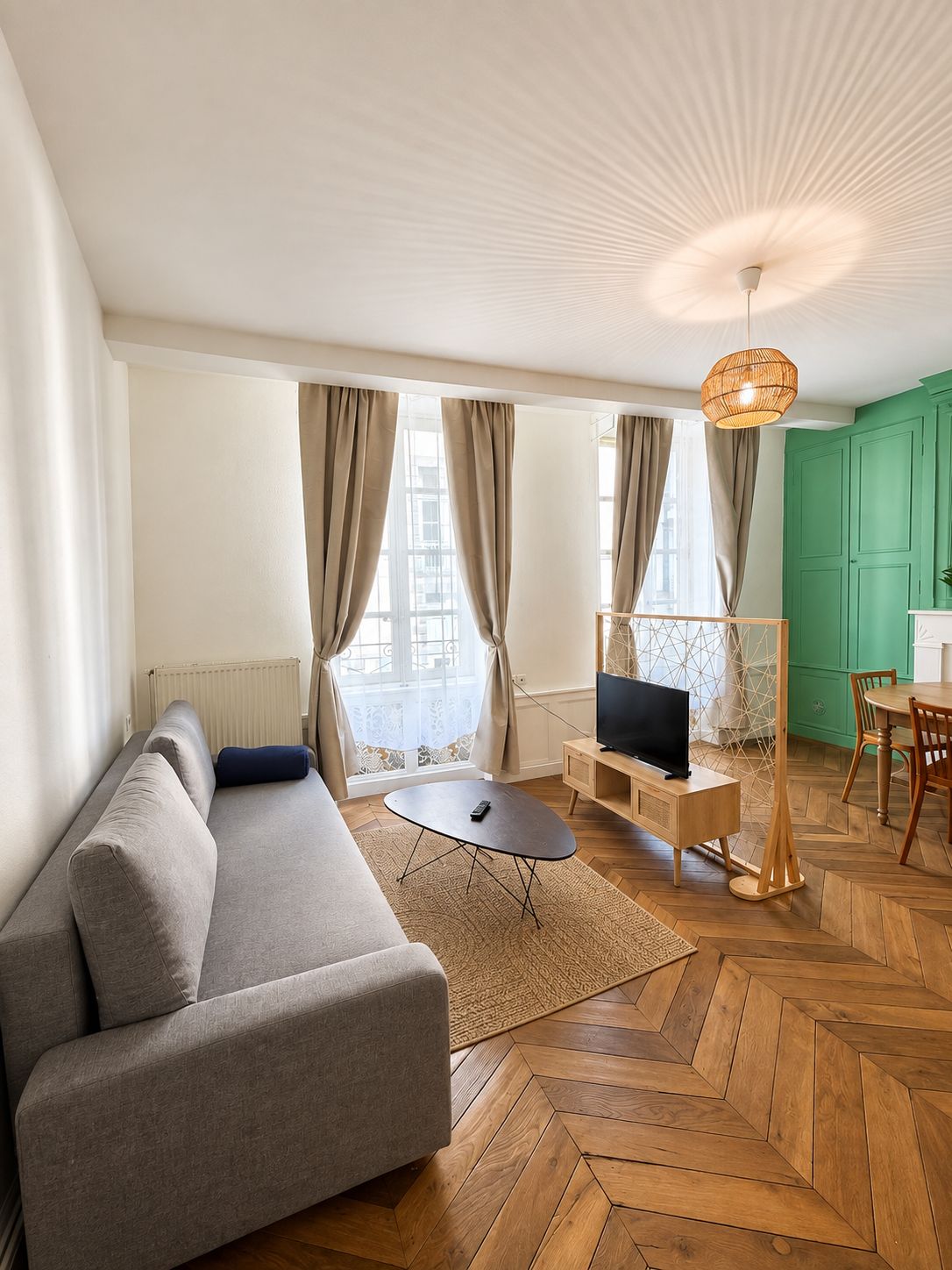 Uma sala de estar moderna com sofá, painel para TV e área de refeições.
