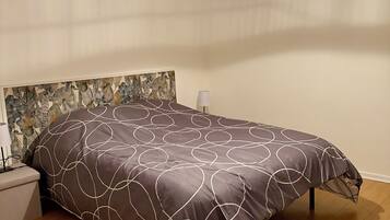 Een slaapkamer met een groot bed, een plafondventilator en een wandlamp.