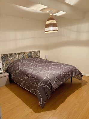 A bedroom with a large bed, a ceiling fan, and a wall-mounted light fixture. - L'émeraude - Charming Apartment in Riom (Riom)