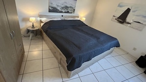 Quarto com cama, duas luminárias de cabeceira, mesa de cabeceira e um quadro na parede.