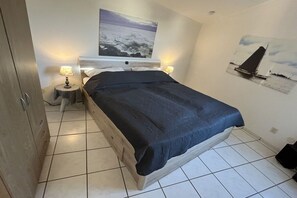 Ett sovrum med en säng, två sänglampor, ett nattduksbord och en tavla som hänger på väggen.