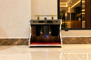 Una máquina de espresso estacionaria con interior rojo, ubicada sobre un piso de mármol pulido en un ambiente interior moderno.