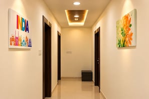 A hallway with two doors, a ceiling light, and two artworks on the walls. - Hotel Rakesh Grand Hyderabad (Hyderabad)