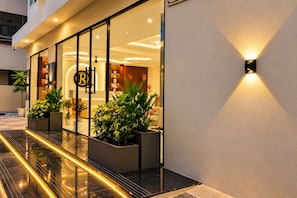 A modern hotel entrance with a glass facade, indoor plants, and a well-lit exterior. - Hotel Rakesh Grand Hyderabad (Hyderabad)