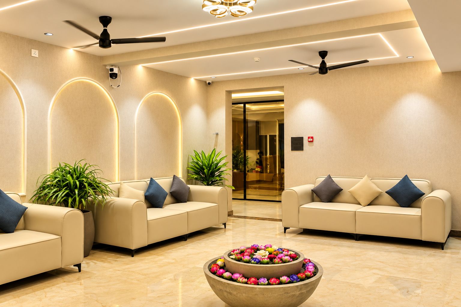 A modern lobby with two sofas, ceiling fans, and a flower arrangement.