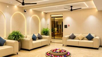 A modern lobby with two sofas, ceiling fans, and a flower arrangement.