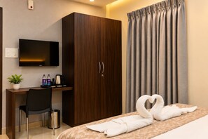 Habitación de hotel con una cama, un escritorio con silla, televisión, armario y cortina.